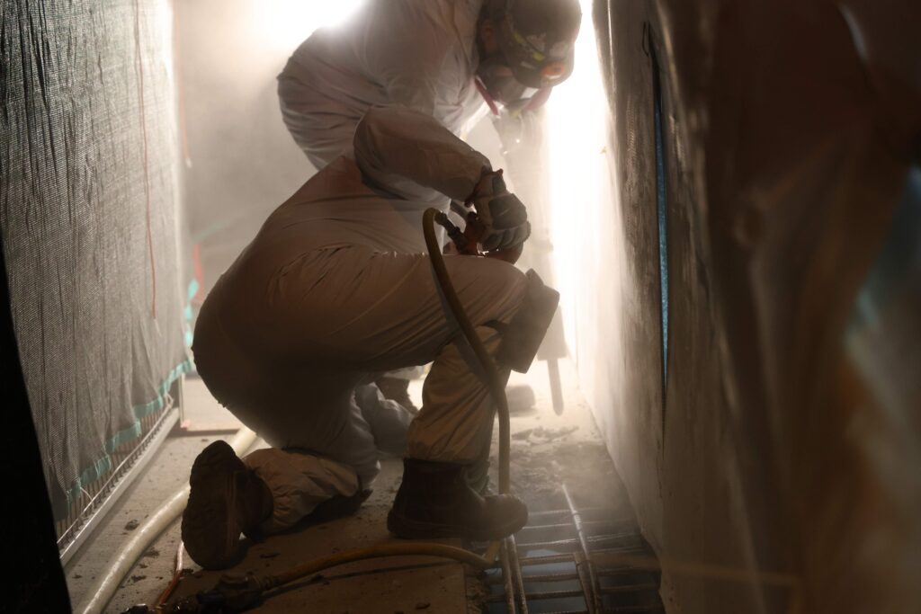 Two individuals in white attire repairing a wall